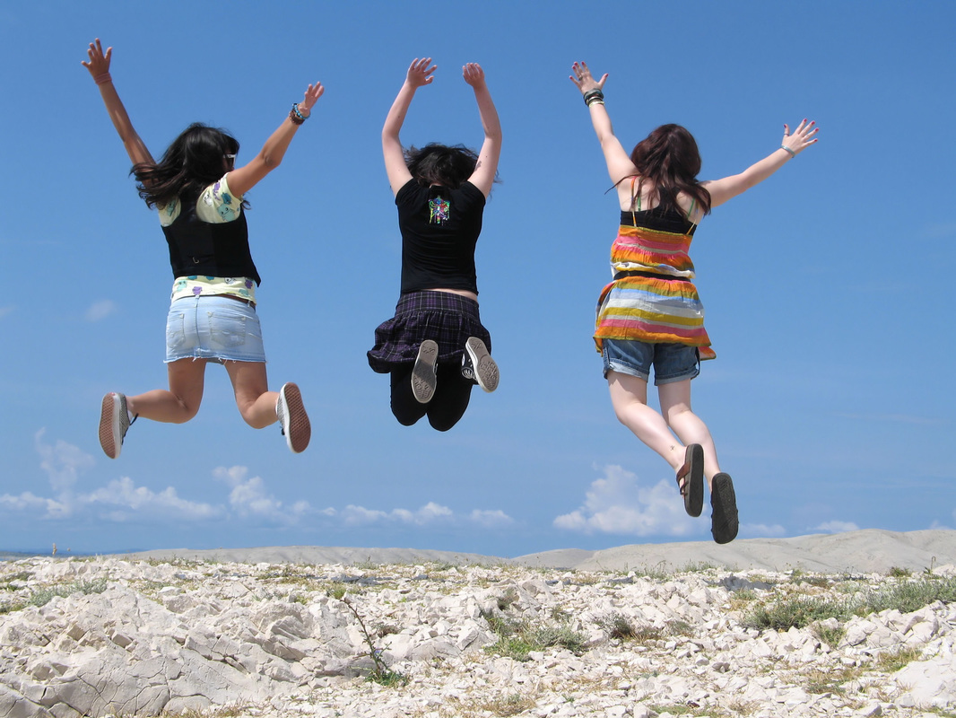 Image: three girls jumping with their arms in the air